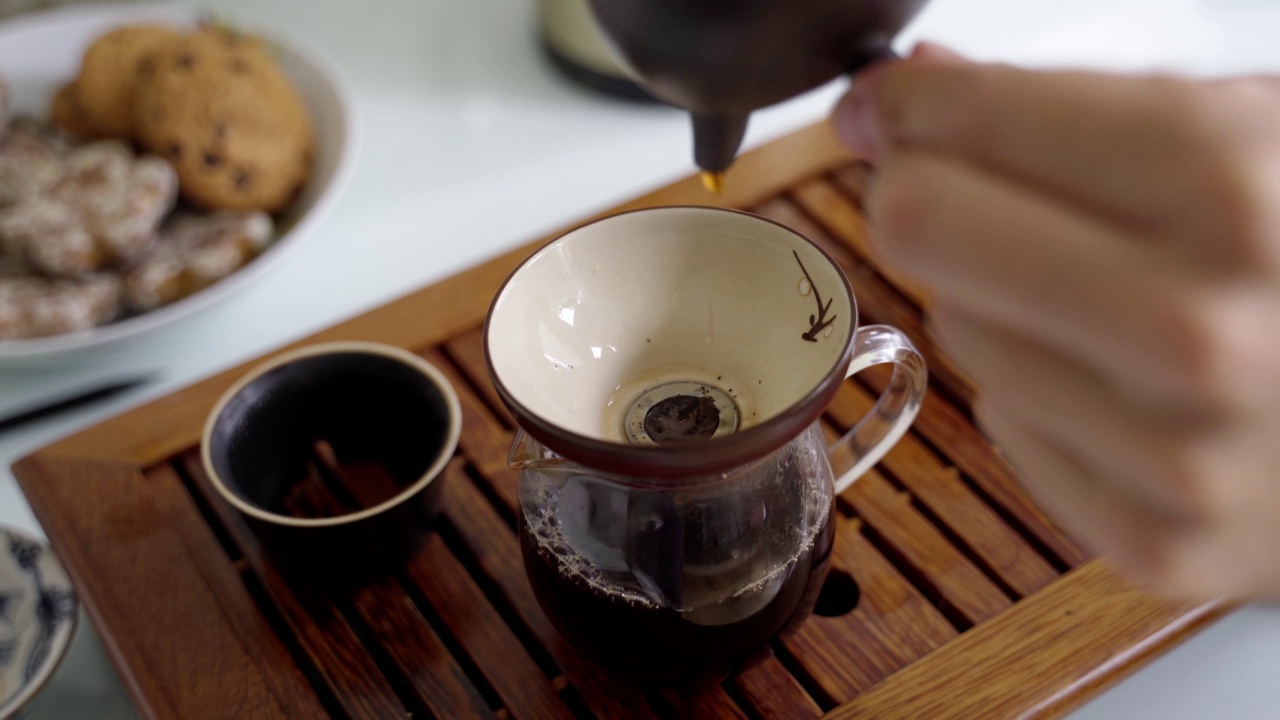 茶道在便携式小桌上。茶叶从一个小茶壶倒入一个特殊的碗，使其味道充满氧气视频素材