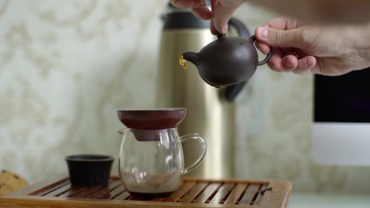 茶道在便携式小桌上。茶叶从一个小茶壶倒入一个特殊的碗，使其味道充满氧气视频素材