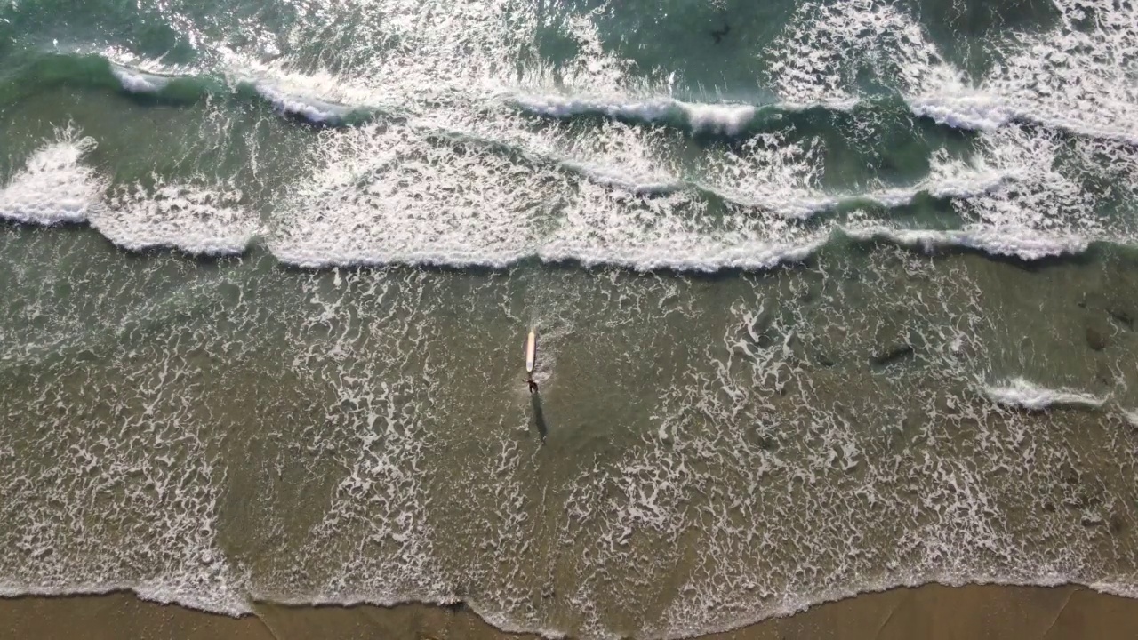 冲浪者在海滩上与海浪的航拍视频素材