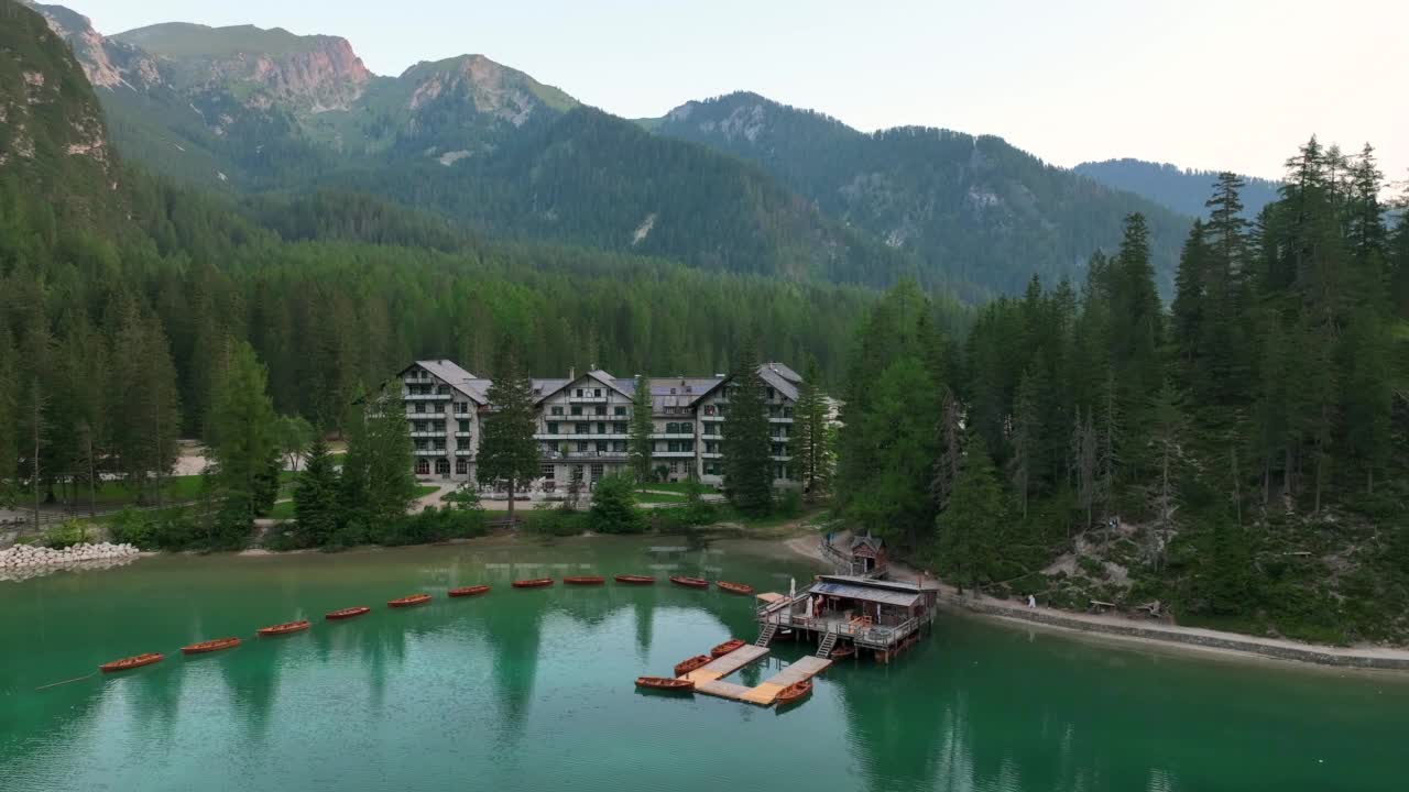 无人机查看最美丽的拉戈迪布雷斯的日出场景，也被称为Pragser Wildsee。白云石山脉,意大利。飞出碧绿平静的水面，船在生涩。视频素材