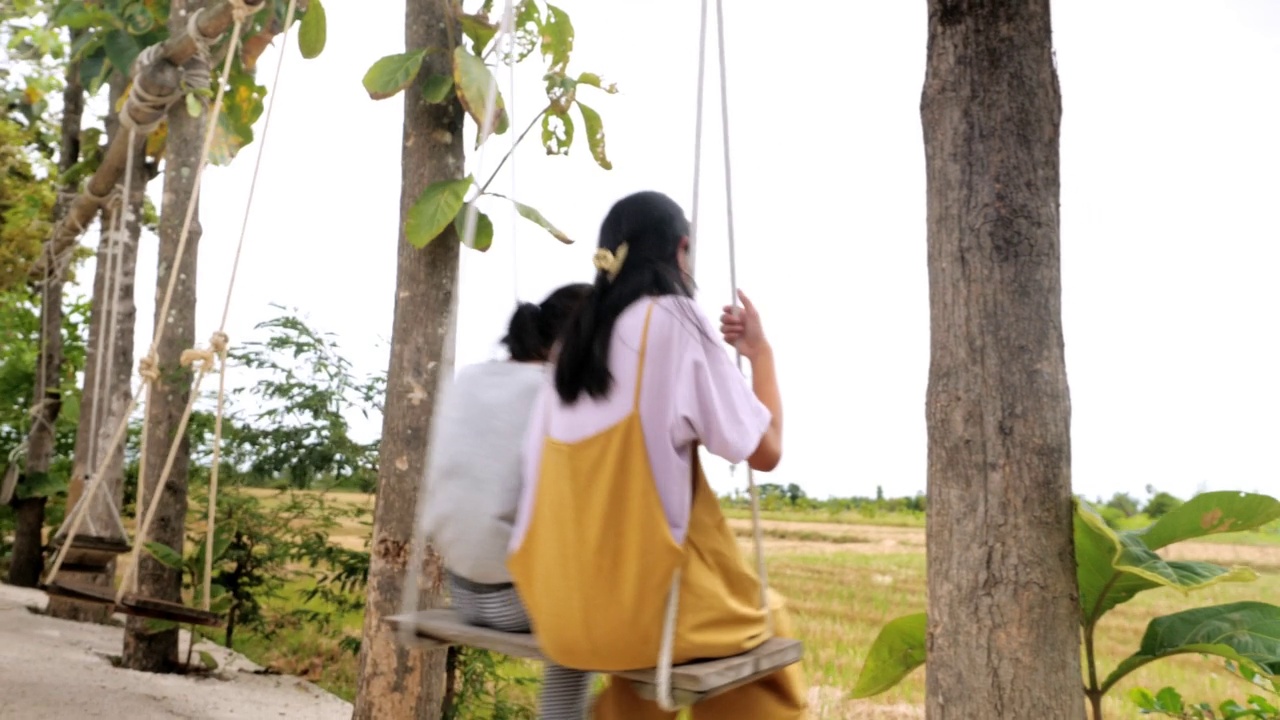 亚洲女孩一起玩荡秋千和看稻田风景，生活方式的概念。视频素材