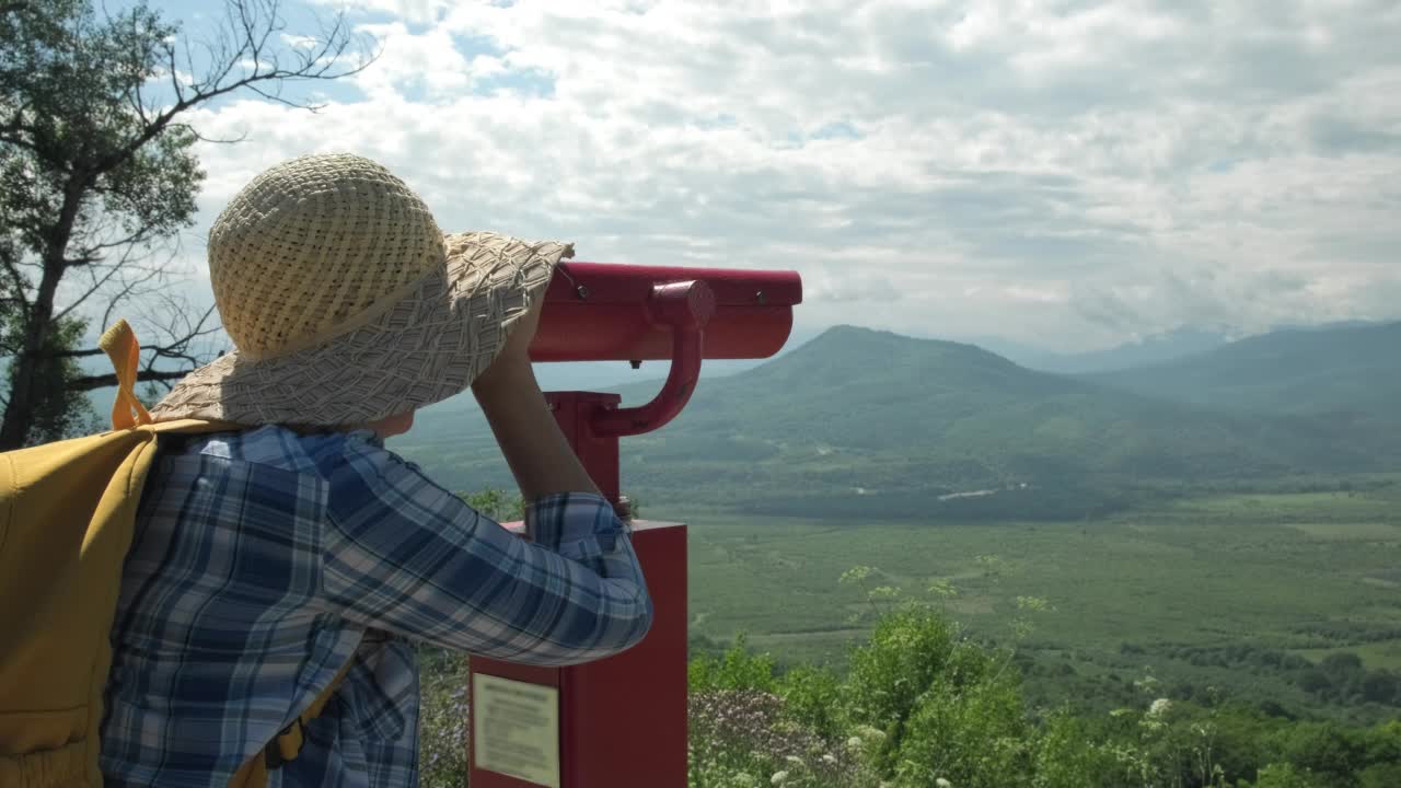 度假旅行中的女人在山上用硬币操作的双筒望远镜看东西视频素材