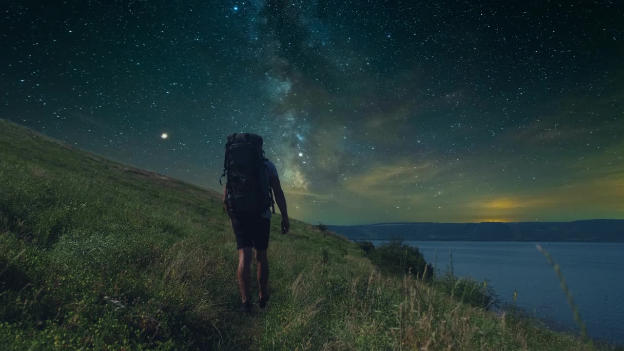 在星空的背景下，一个人沿着山岸徒步旅行。慢动作视频素材