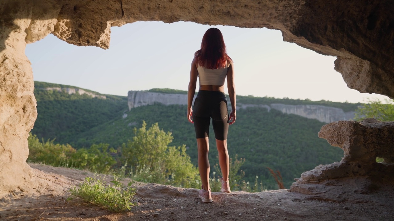 穿着运动服的苗条女人旅行者穿过洞穴走向出口视频素材