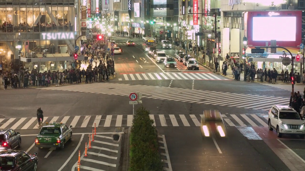 在日本东京，许多行人和车辆在夜间穿过路口的涩谷十字路口视频素材