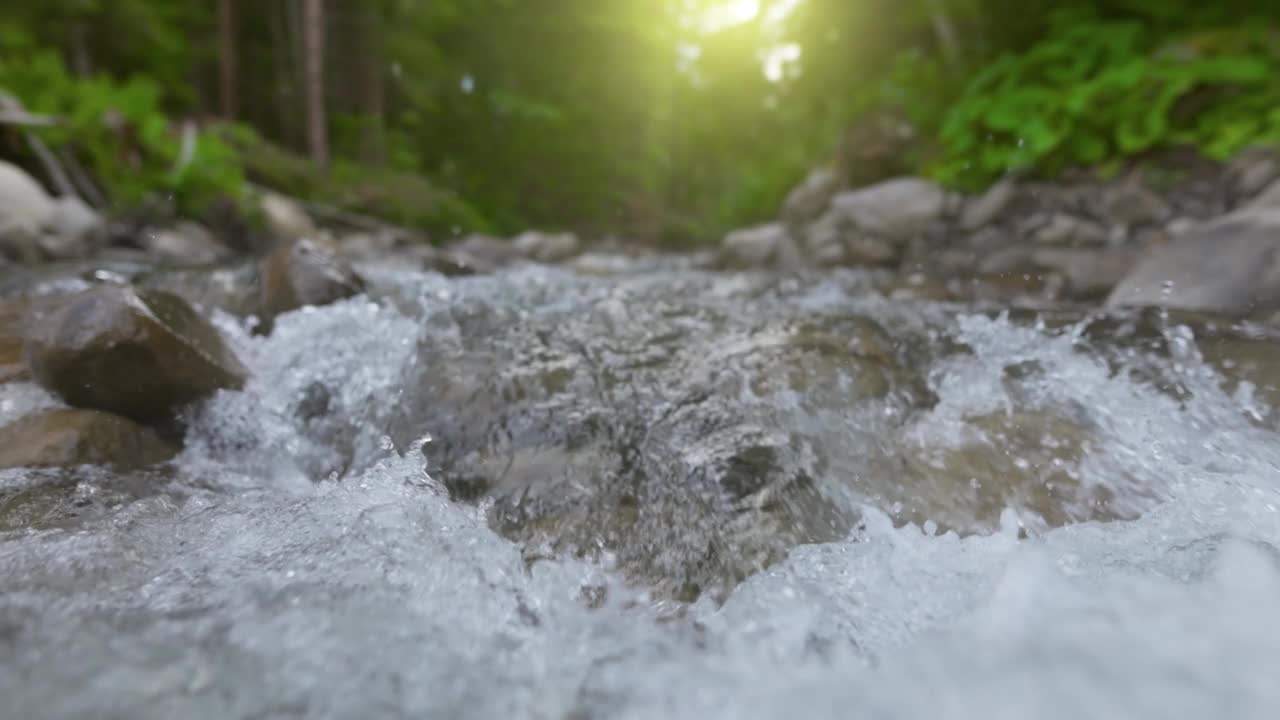 森林中湍急的山河的慢动作镜头。山河清澈的水在石头之间流动的云台镜头视频素材