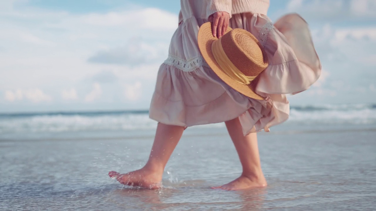 B滚-沙滩上女人的脚沿着海浪走，夏季旅游度假的女游客，慢动作视频素材