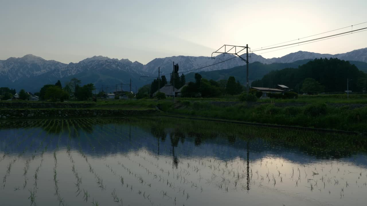 短短的两节车厢和春天稻田映照的雪山视频素材