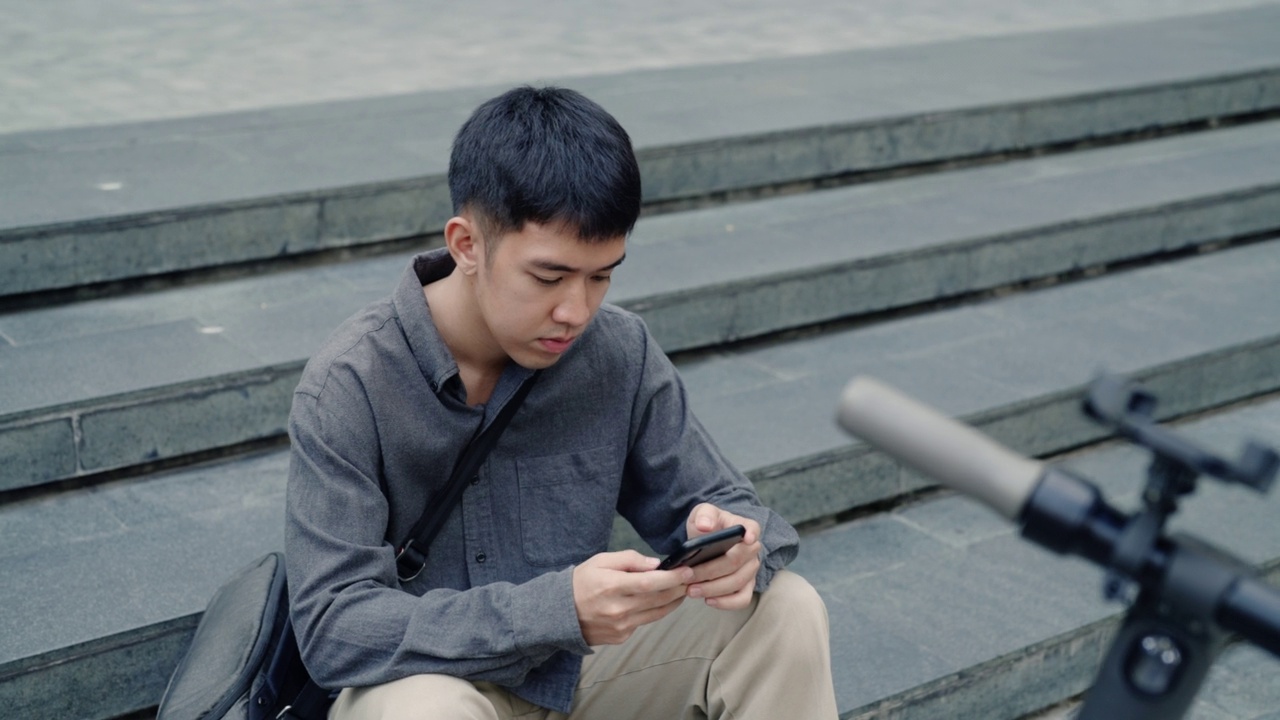 一名亚洲男子用手机app租电动车。视频素材