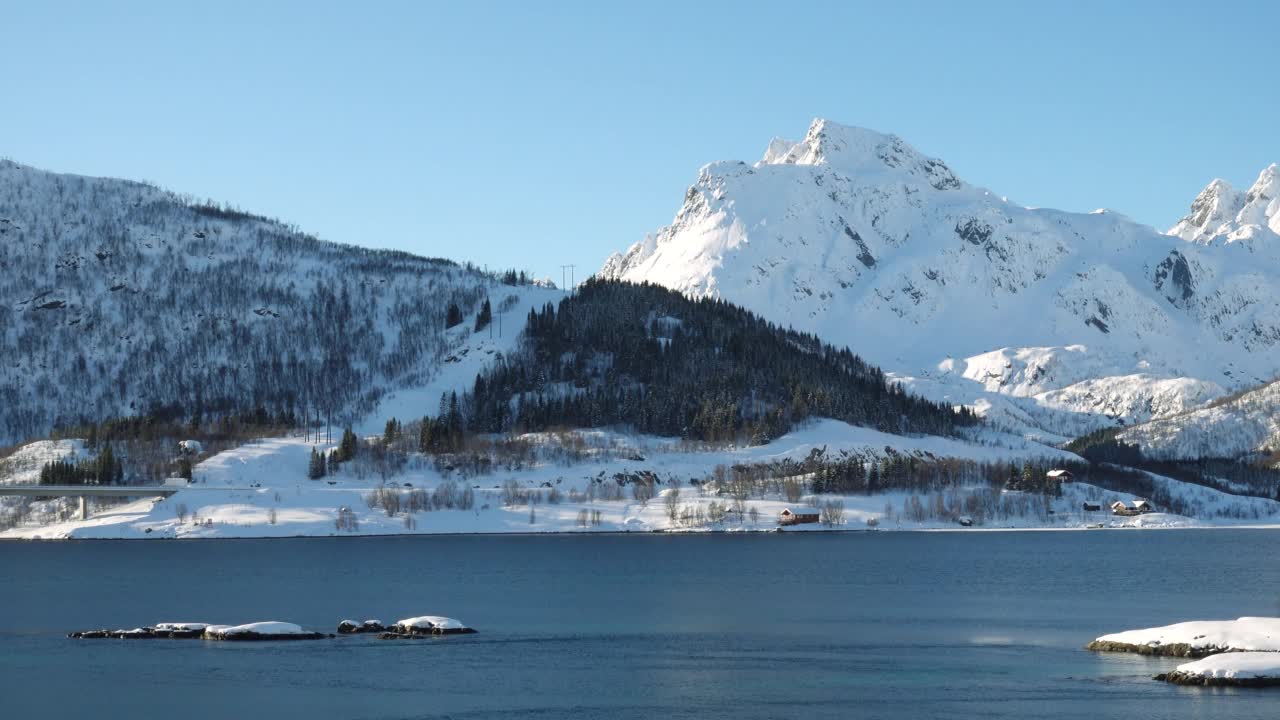 挪威冬季全景图，海边的房子和远处美丽的雪山视频素材