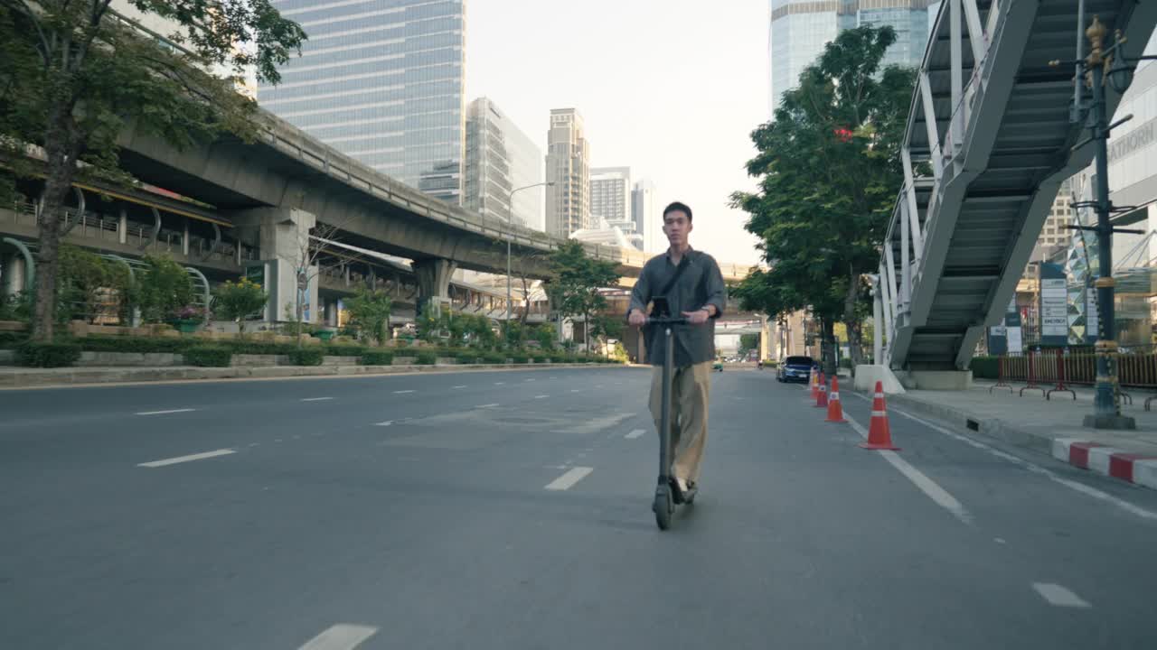 一个年轻人骑着电动车沿着城市街道的小路行驶。视频素材