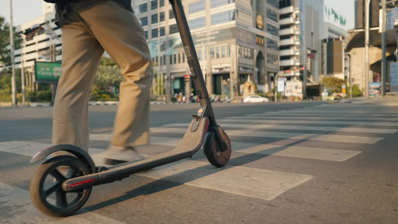 一个年轻人骑着电动车沿着城市街道的小路行驶。视频素材