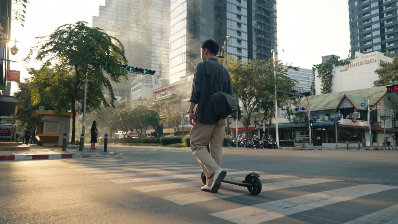 一个年轻人骑着电动车沿着城市街道的小路行驶。视频素材