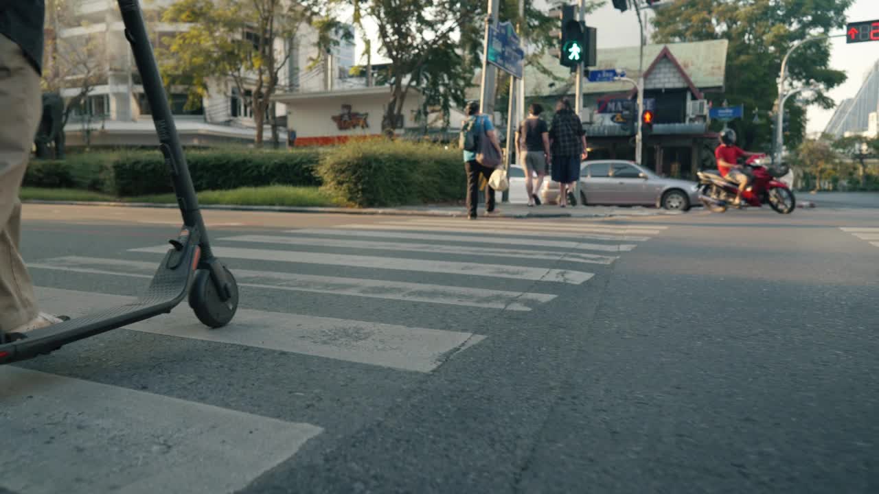 一个年轻人骑着电动车沿着城市街道的小路行驶。视频素材