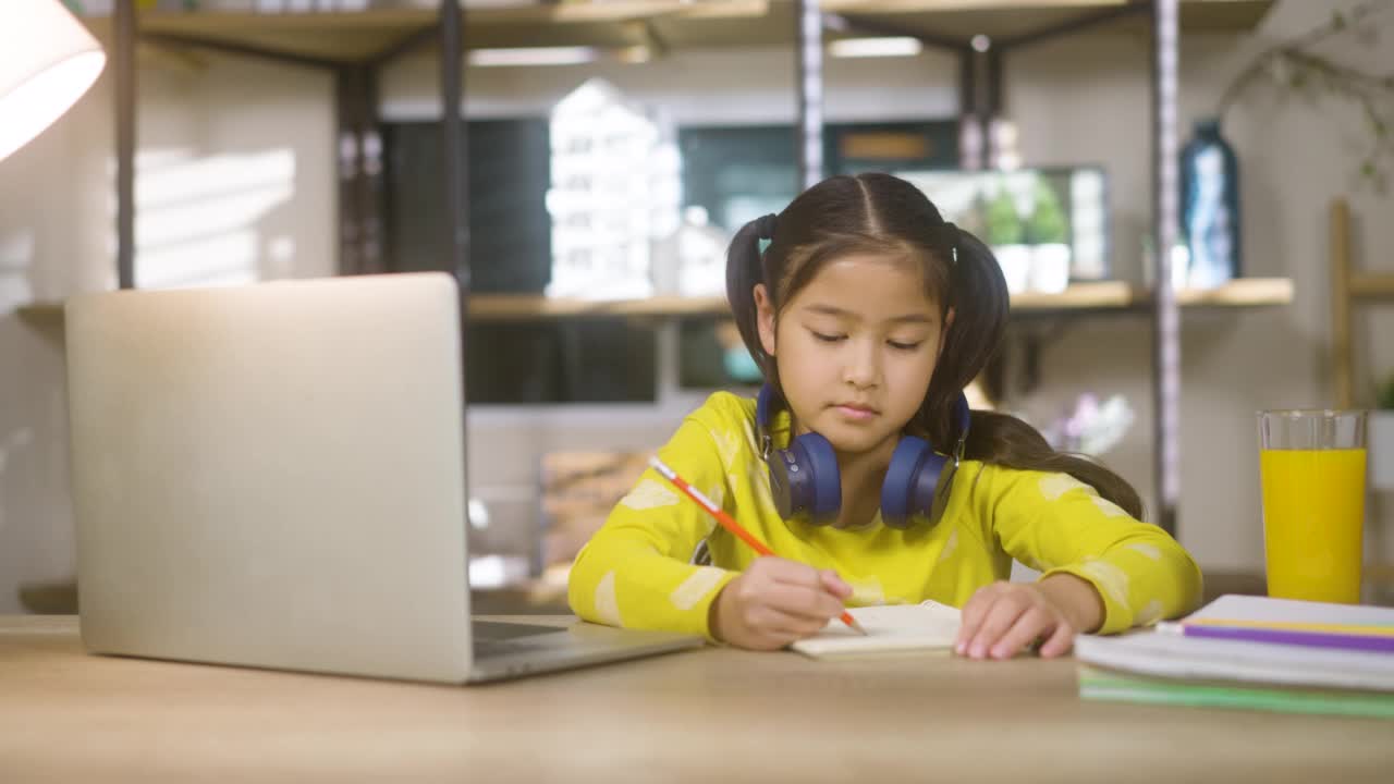 年轻的亚洲可爱的女孩在家里用笔记本电脑学习视频素材