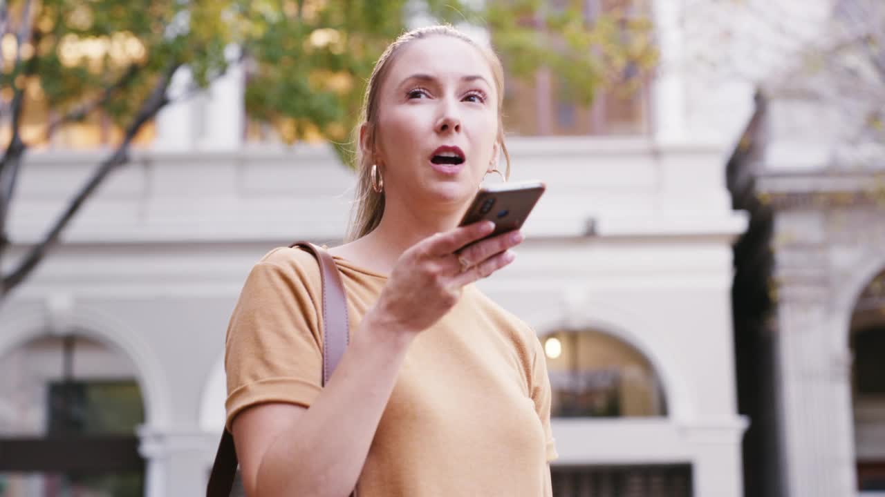 女人在上下班、旅行和在城市站着的时候打电话。微笑的女性通过语音指令或语音助手问路，看起来很开心视频素材