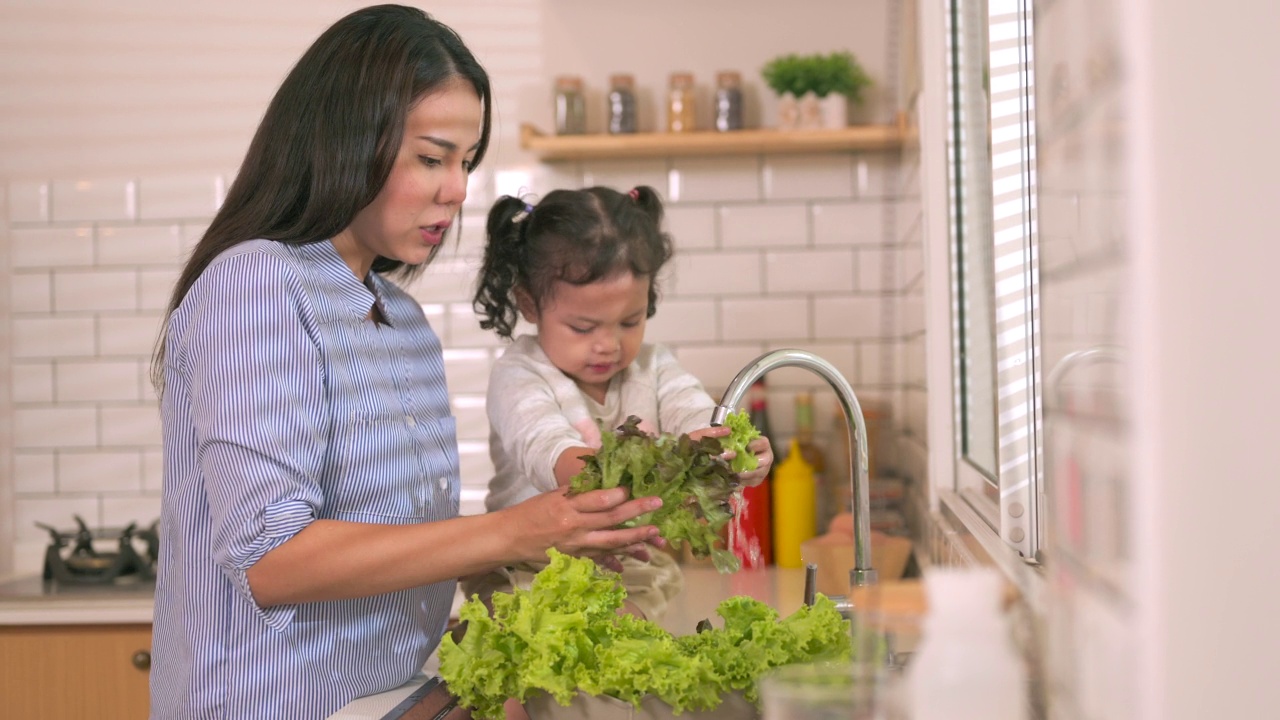 小女儿正在厨房帮妈妈洗菜。视频素材