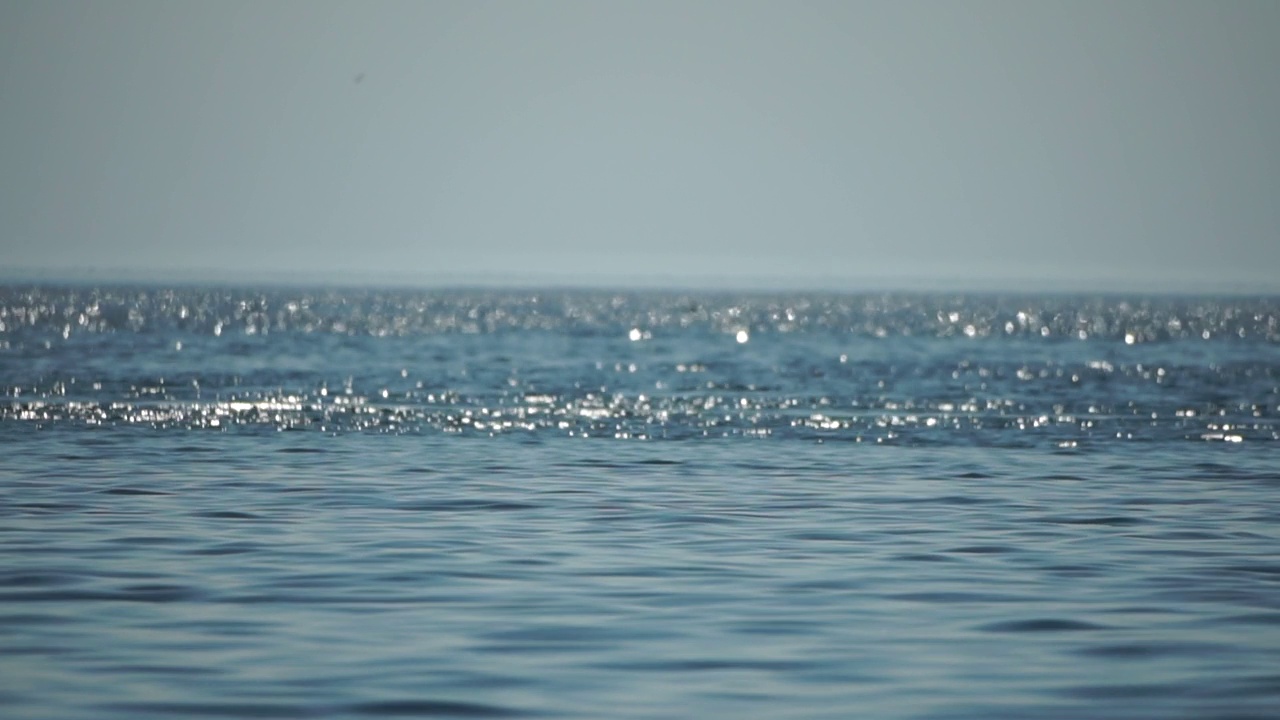 抽象海洋夏季海洋日落自然背景。小波浪水面上的运动模糊与金色的散景灯从太阳。度假、度假和休闲的概念。慢动作视频素材