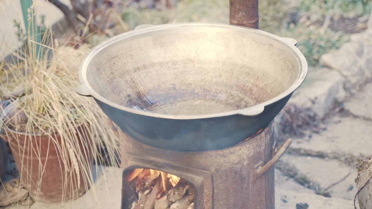 铸铁大锅立在炉子上，有木头和火。视频素材