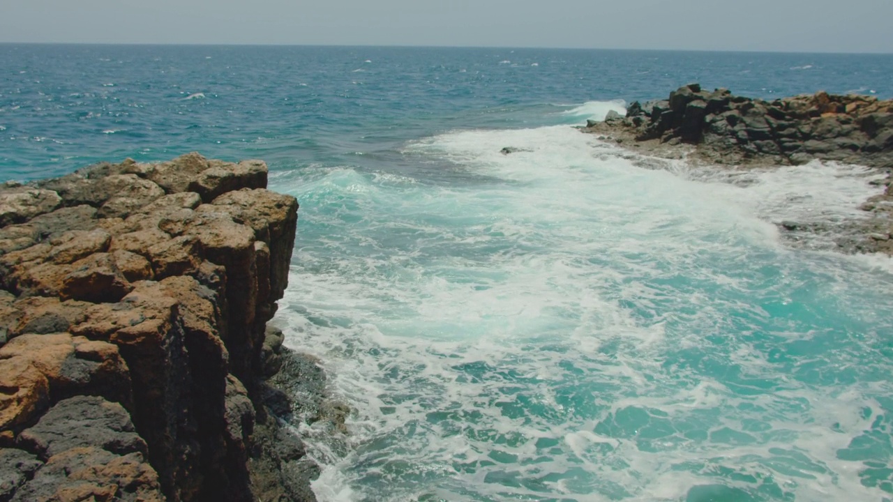 Fuerteventura,加那利群岛。天然游泳池。海浪冲击着空荡荡的岩石黑色海滩。火山石的特写，水花四溅。Castillo Caleta de Fuste镇附近。视频素材