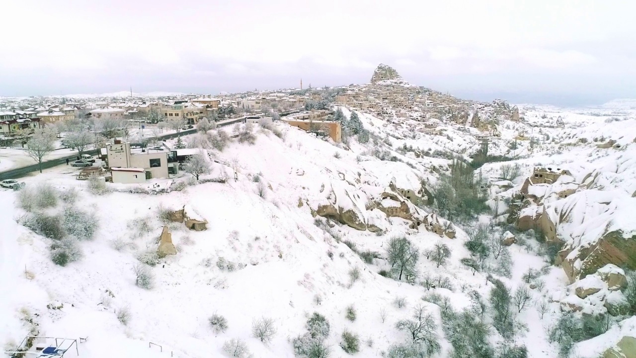 乌治沙石雕城堡和冬季乌治沙城。白雪皑皑的群山。鸟瞰图。卡帕多西亚,土耳其。视频素材