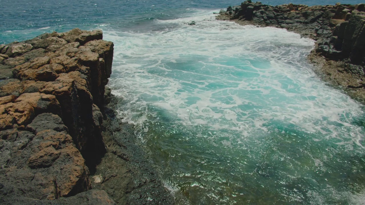 Fuerteventura,加那利群岛。天然游泳池。海浪冲击着空荡荡的岩石黑色海滩。火山石的特写，水花四溅。Castillo Caleta de Fuste镇附近。视频素材