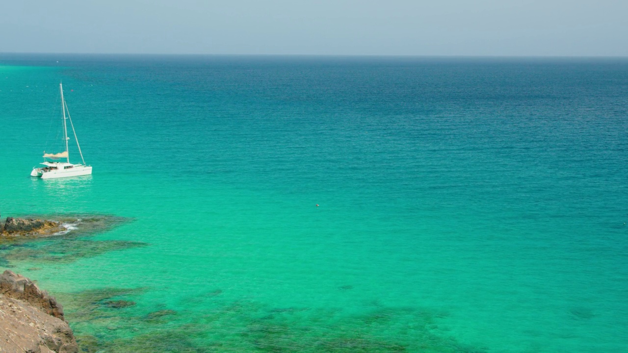 美丽的海洋海岸线和平静放松静观翡翠的海水大海。自然景观令人心旷神怡，容易入眠。白色的帆船漂浮在波浪上。视频素材