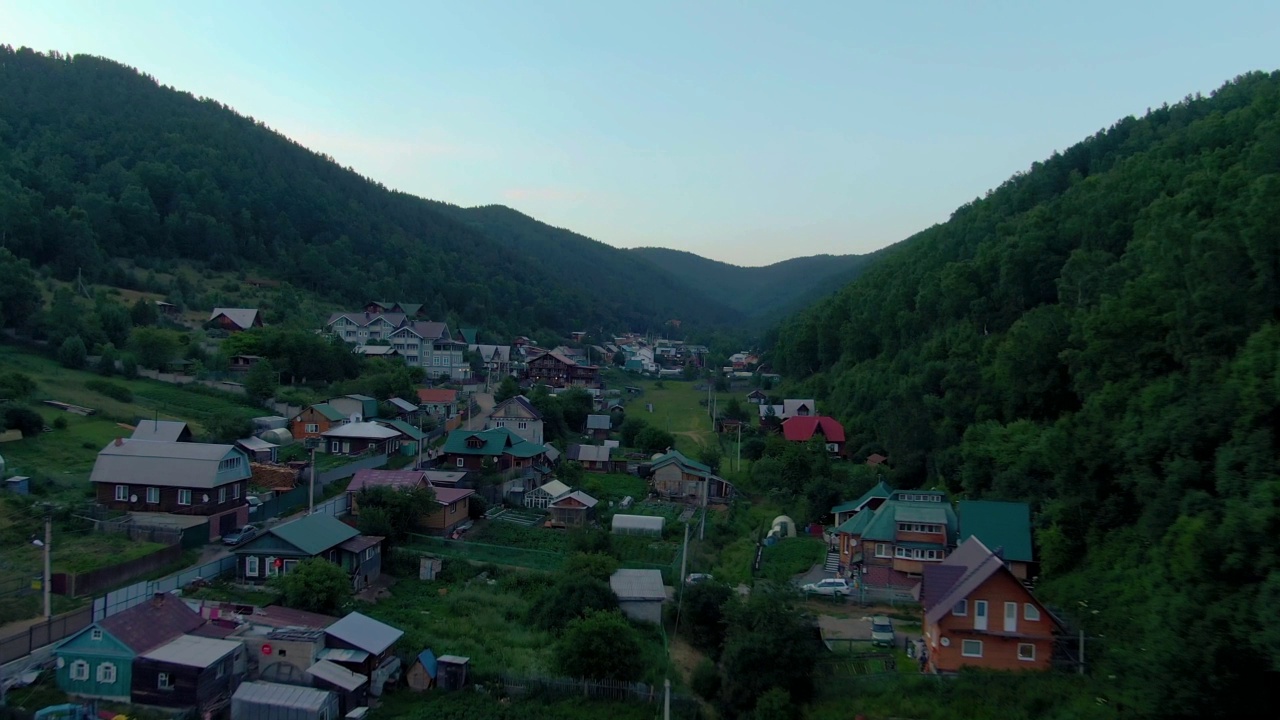 飞越山林间的村庄。人与自然。绿色的山脉。路。空中无人机视频。视频素材