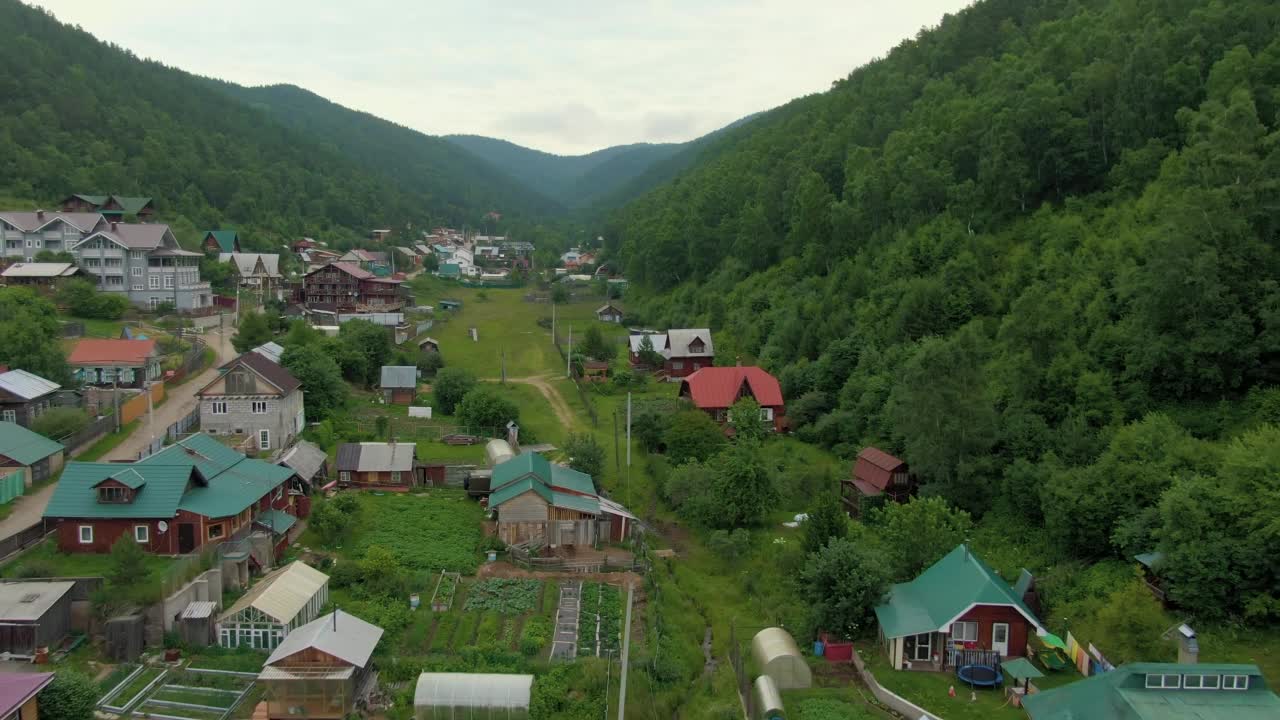 飞越山林间的村庄。人与自然。绿色的山脉。路。空中无人机视频。视频素材