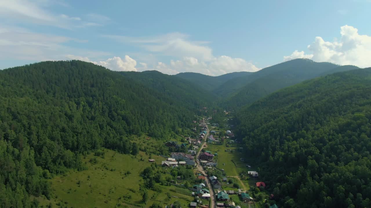 从山顶俯瞰青山之间的村庄。人与自然。绿色的山脉。路。空中无人机视频。视频素材