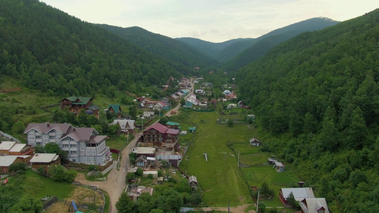 飞越山林间的村庄。人与自然。绿色的山脉。路。空中无人机视频。视频素材