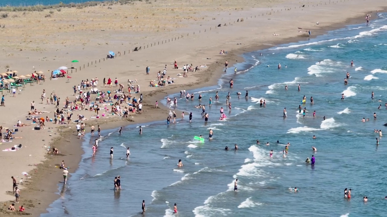 空中的人群，夏天拥挤的海滩的鸟瞰图，在沙滩上，拥挤的人在海里游泳视频素材