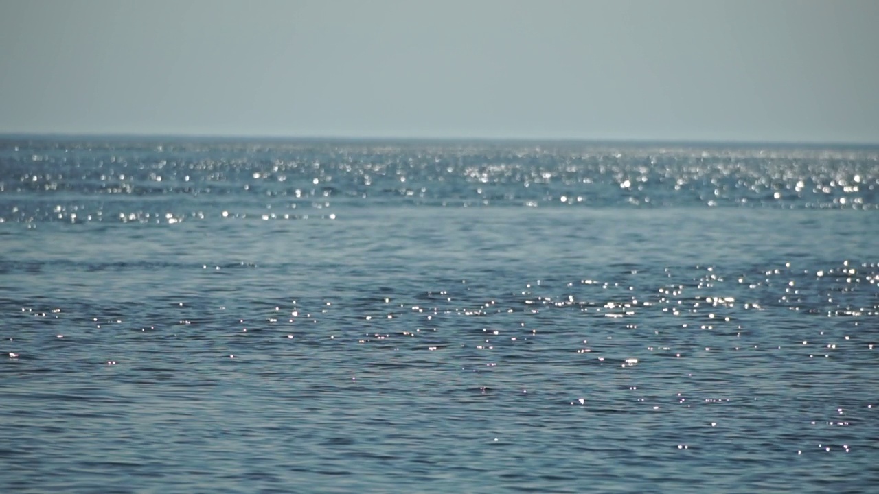 抽象海洋夏季海洋日落自然背景。小波浪水面上的运动模糊与金色的散景灯从太阳。度假、度假和休闲的概念。慢动作视频素材