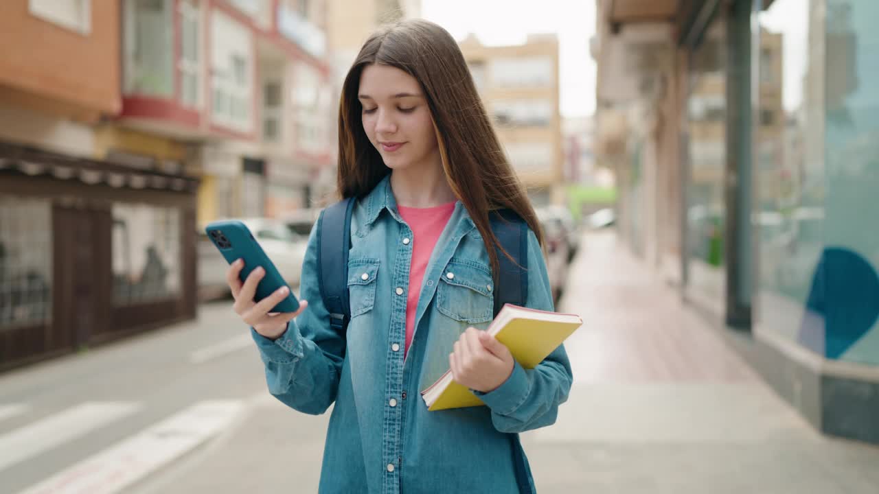 可爱的女学生在街上使用智能手机视频素材