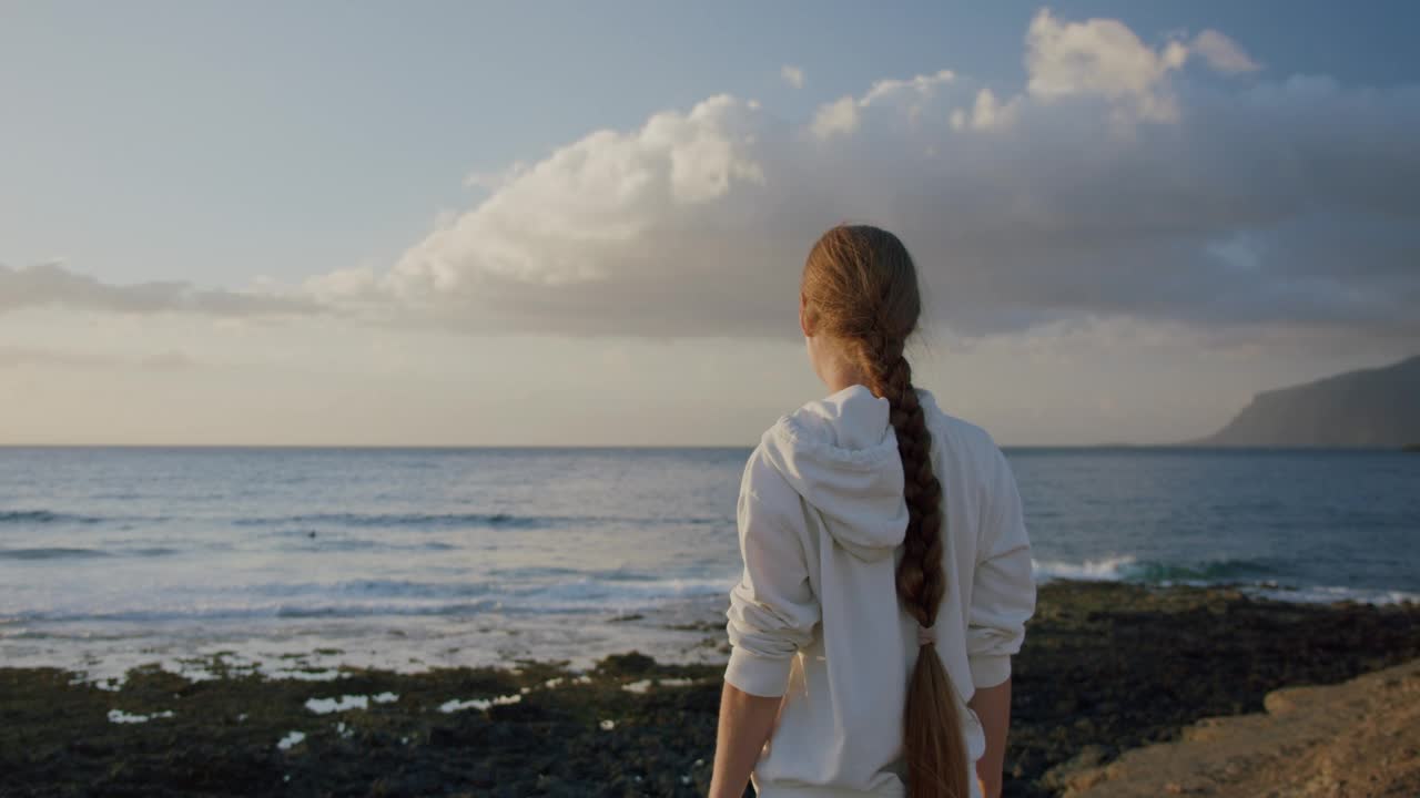 年轻的女子站在面对海洋，享受在海滩上的圣地亚哥港，特内里费视频素材