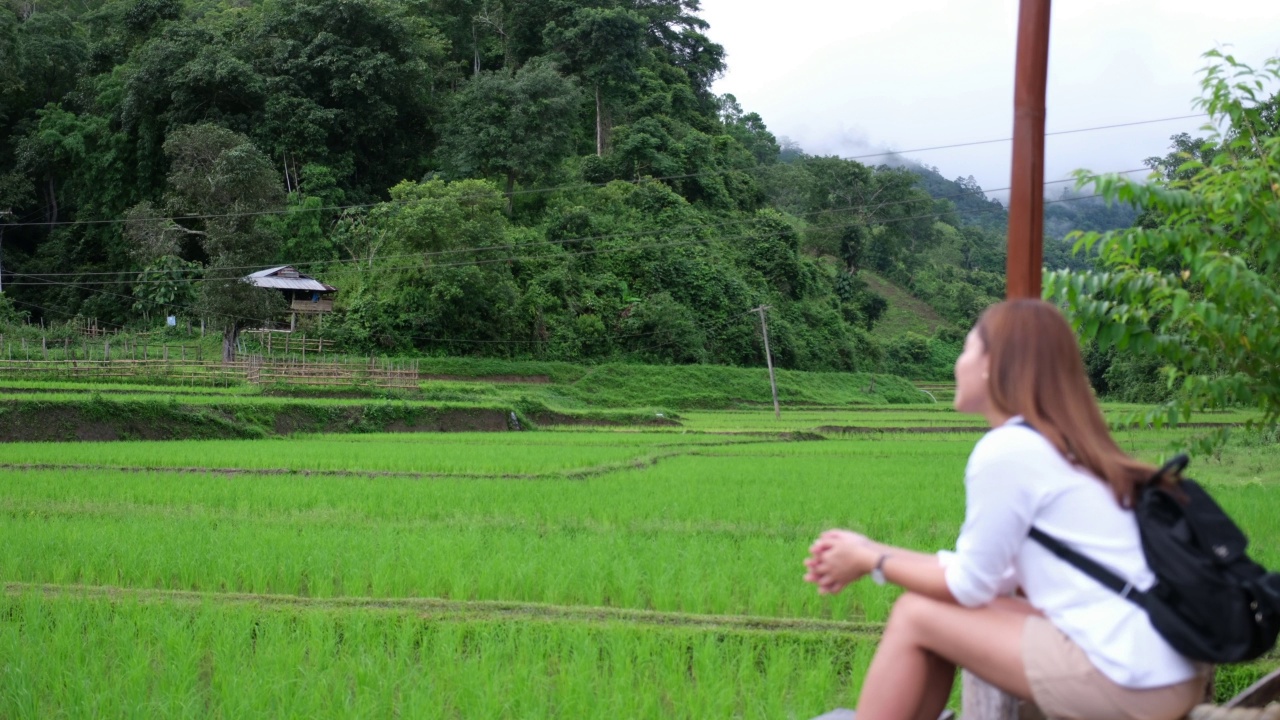 模糊的一个女人坐着，看着稻田或梯田和山景视频素材