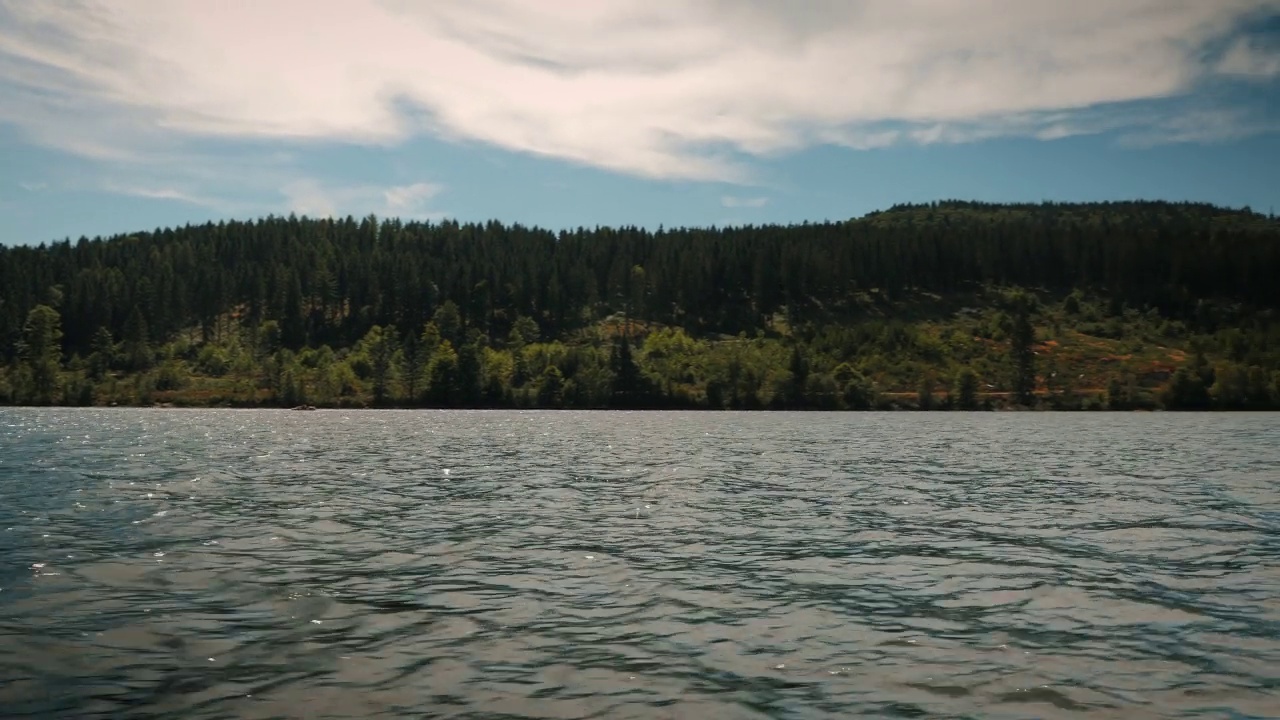 平静的山湖，平静的水和绿色的松树丘陵。漂浮在清澈的湖面上。位于德国自然景观中的蓝山湖泊。山湖上的夏季景观视频素材