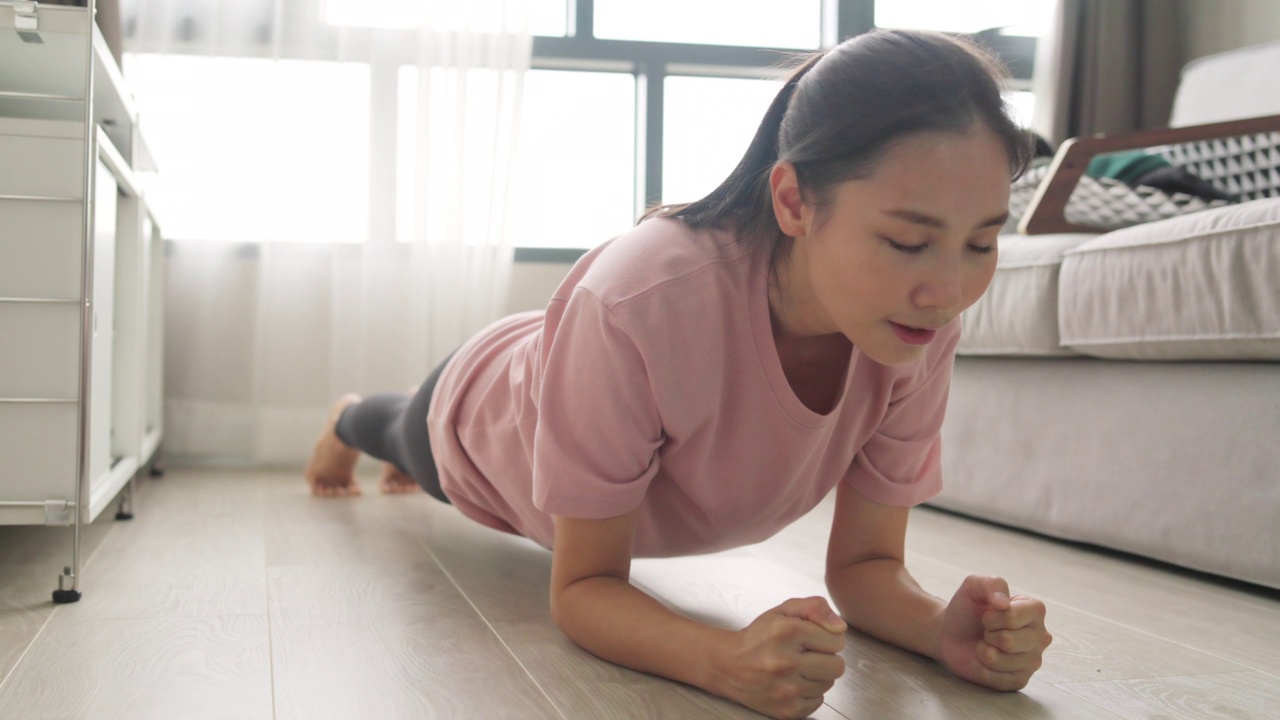 4K年轻的亚洲妇女在客厅的笔记本电脑上观看在线教程学习锻炼。视频素材