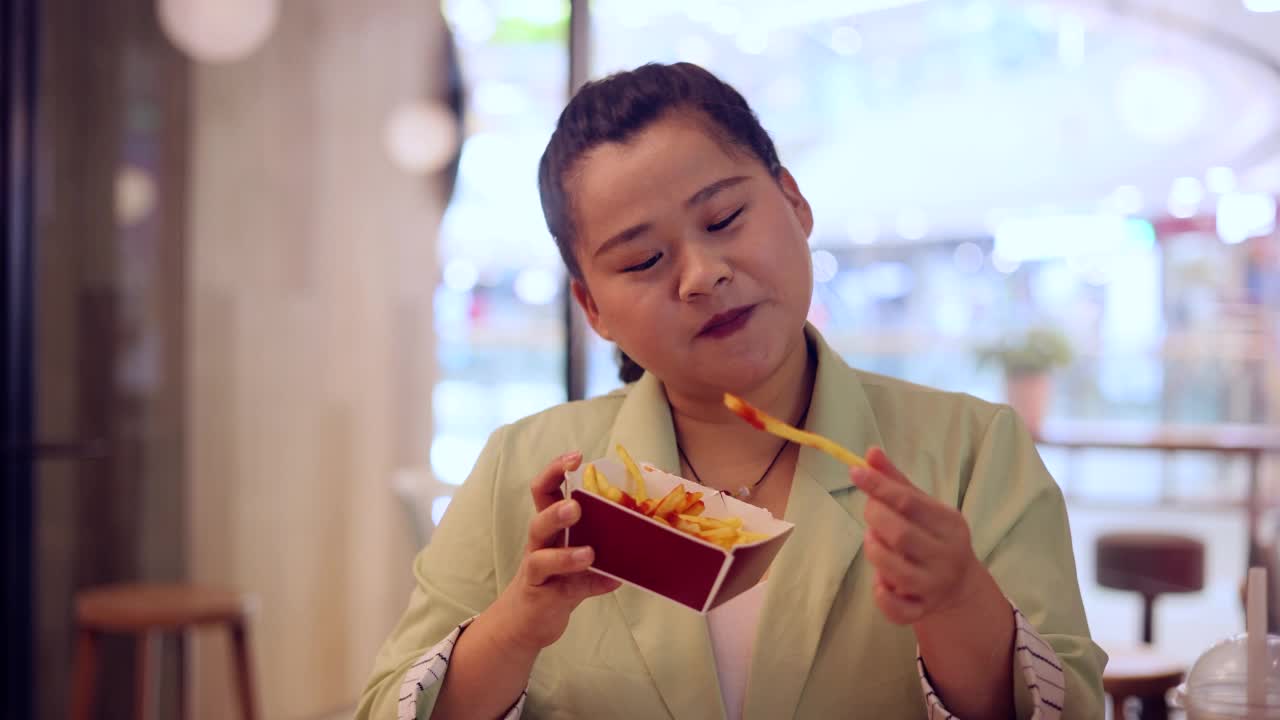 超重女性吃炸薯条视频素材