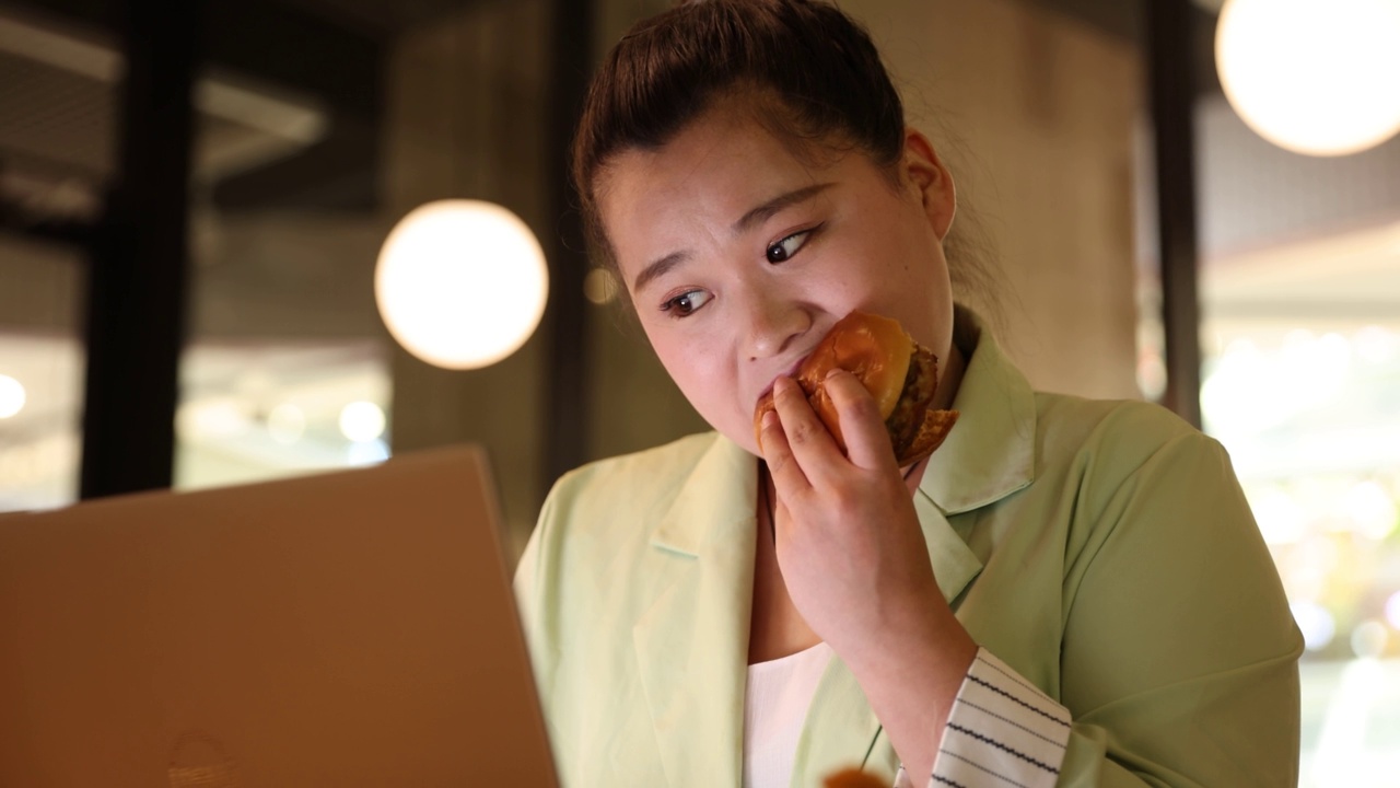 女商人一边吃快餐，一边用笔记本电脑工作视频素材