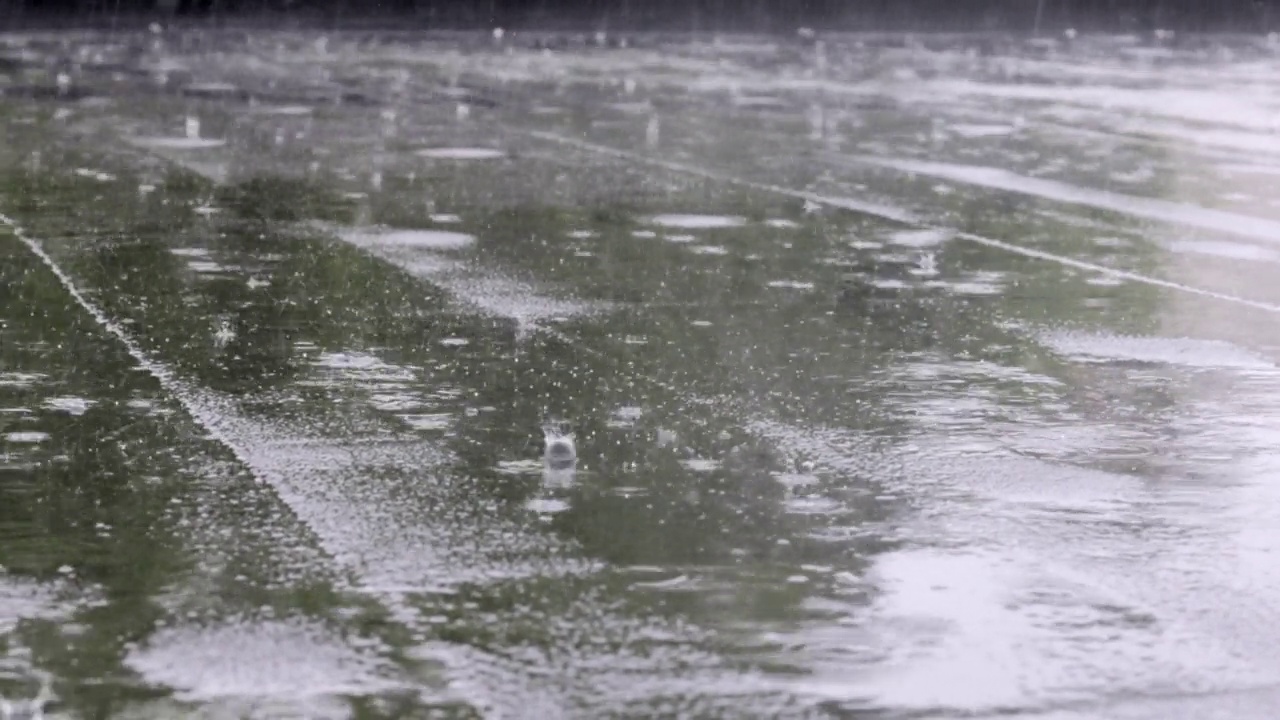 雨点敲打着屋顶，大雨滂沱。这座建筑的平屋顶覆盖着防水材料，可以防雨。橡胶、卷材屋面及防水材料。视频素材