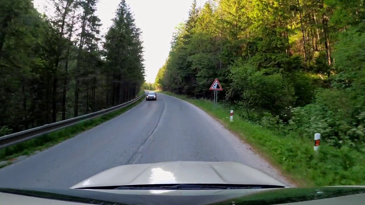 POV拍摄的一辆汽车沿着森林和山脉的道路行驶。夏天开车旅行视频素材