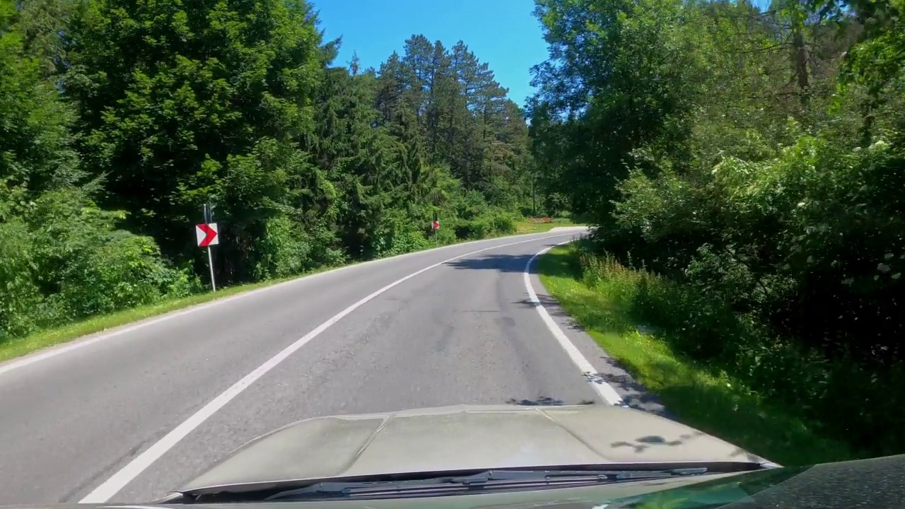 POV拍摄的一辆汽车沿着森林和山脉的道路行驶。夏天开车旅行视频素材