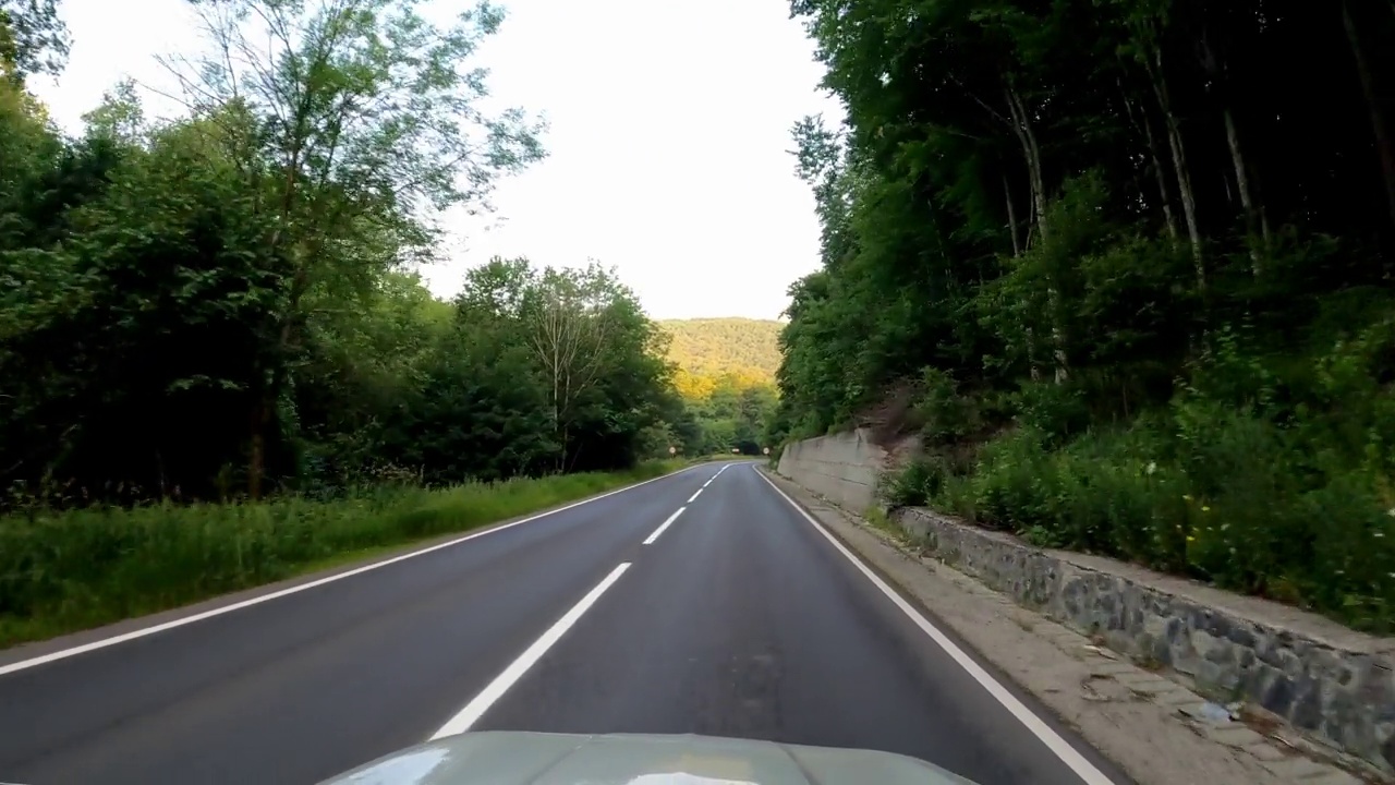 POV拍摄的一辆汽车沿着森林和山脉的道路行驶。夏天开车旅行视频素材