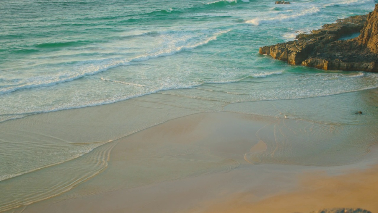 Fuerteventura,加那利群岛。日落时，长长的海浪拍打在白色的沙滩上。海水飞溅在美丽的石灰岩悬崖，海边。自然电影景观。视频素材