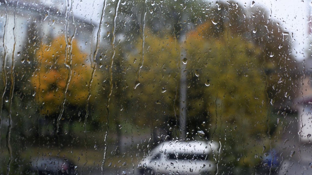 窗外的雨，雨滴落在玻璃上，糟糕的秋日阴雨天气，城市景观，汽车行驶在道路上。视频素材