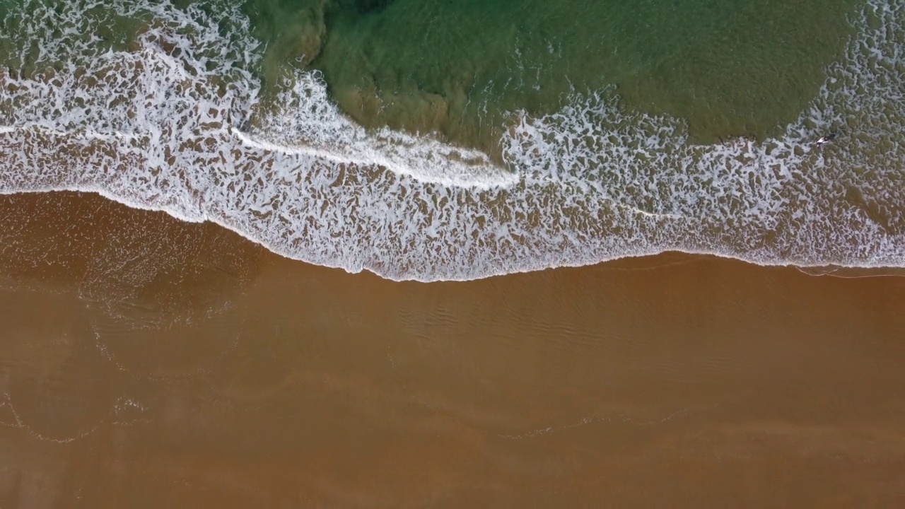 无人机视频在4k的鸟瞰图和移动的海浪在海滩的岸边视频素材