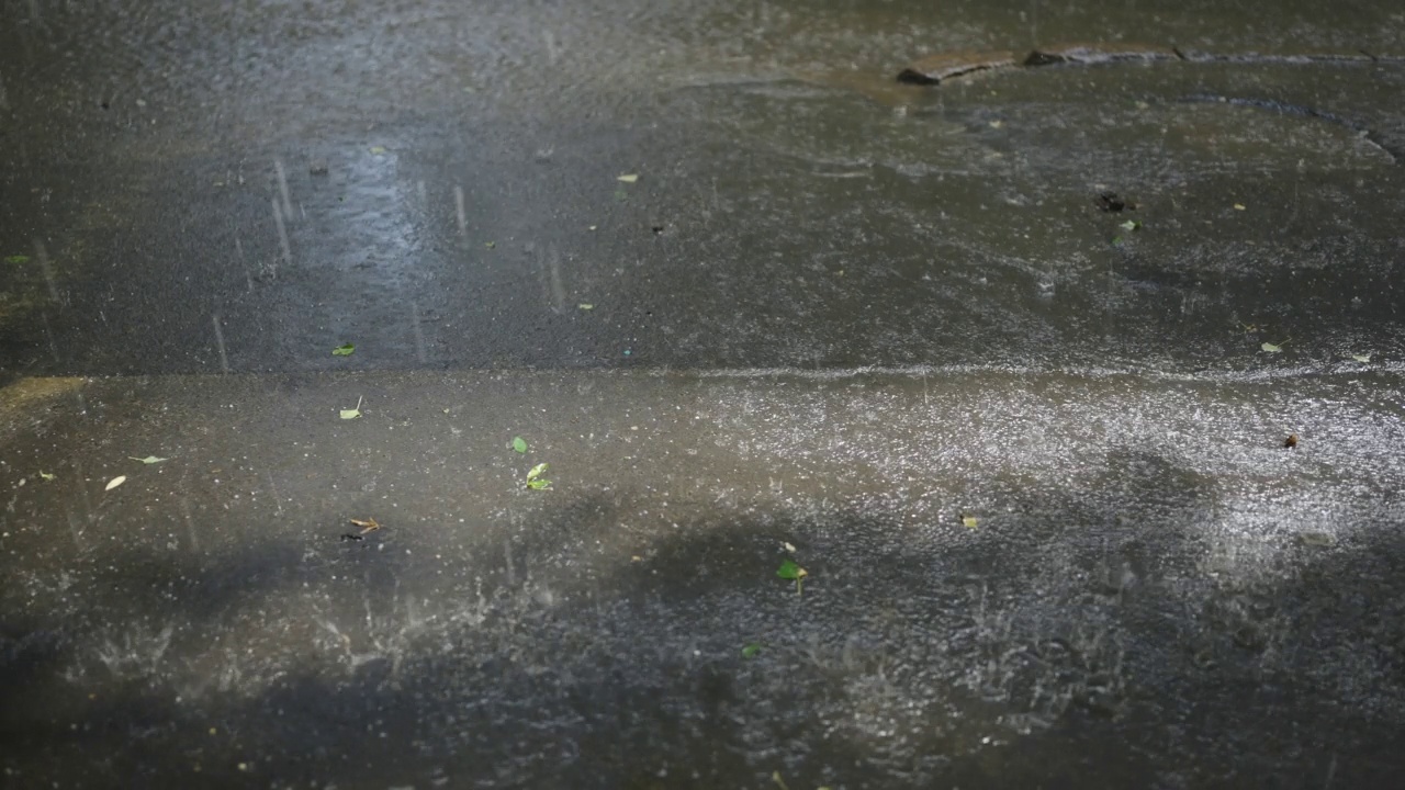 雨滴和冰雹落在柏油路上的特写。慢动作视频素材