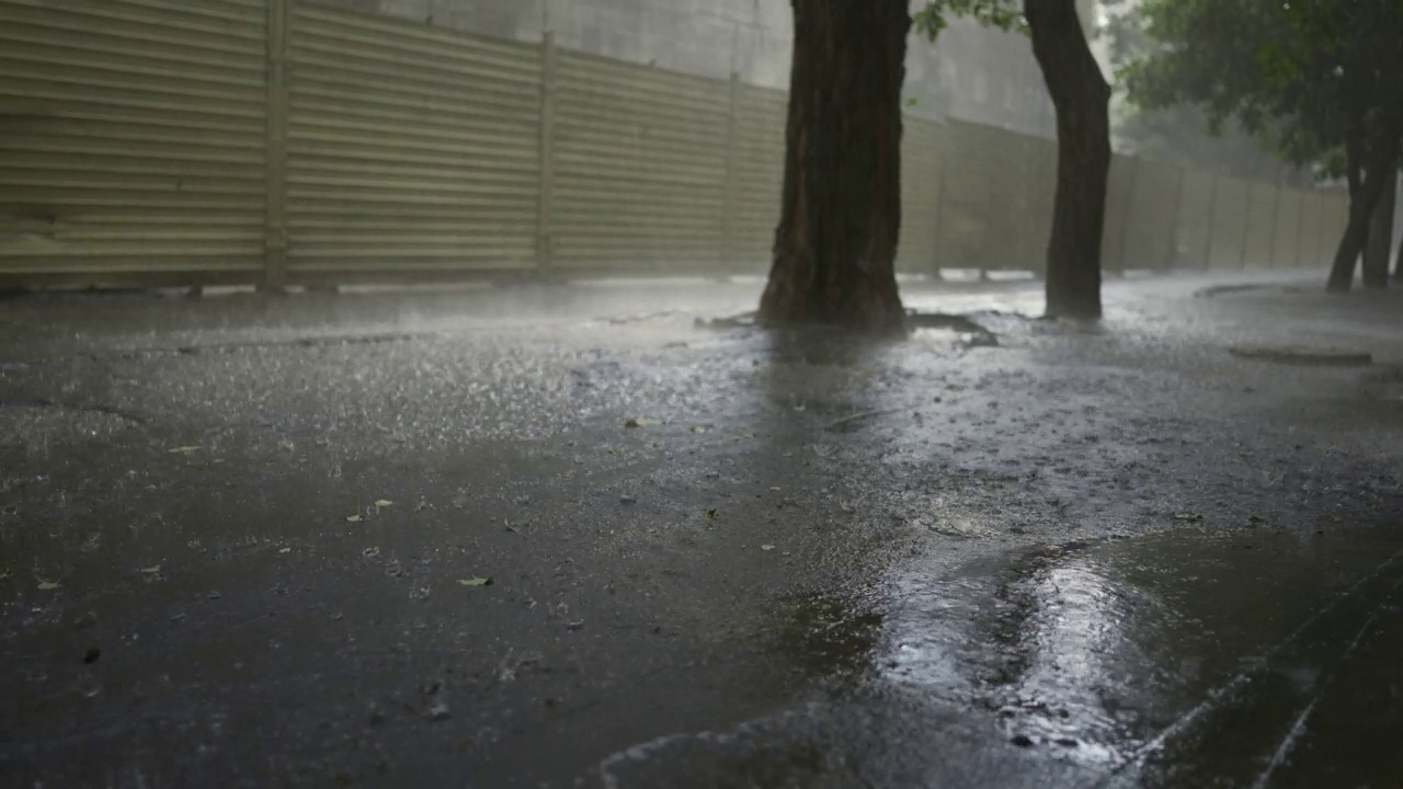 慢镜头，城市里的倾盆大雨。雨滴落在柏油路上视频素材