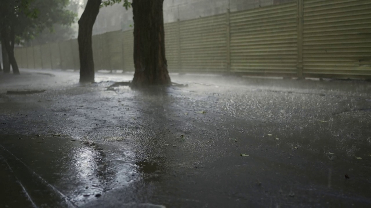 慢镜头，城市里的倾盆大雨。雨滴落在柏油路上视频素材